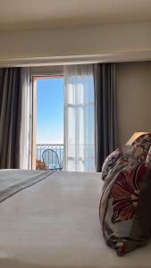 a bedroom with a large bed with a large window at Hôtel Des Gouverneurs in Bastia