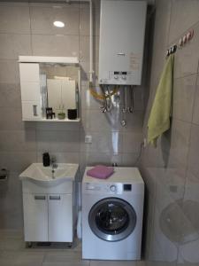 a small bathroom with a washing machine and a sink at Apartman Arija in Ruma