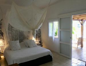 um quarto com uma cama com lençóis brancos e uma janela em MANGOBELO entre océan et rivières em Capesterre-Belle-Eau