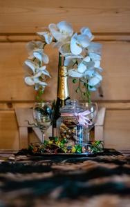 a table with a bottle and glasses and flowers at Domki Dream House ,,Jędruś" in Poronin
