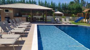 a pool with chaise lounge chairs and a resort at Village 2 suítes beira mar Itacimirim in Camaçari