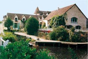 een groot huis met een vijver ervoor bij Les Etangs de Guibert in Neufchâtel-en-Saosnois