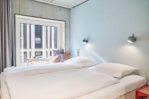 a large white bed in a room with a window at Villa Viva - ein Haus das Brunnen baut in Hamburg
