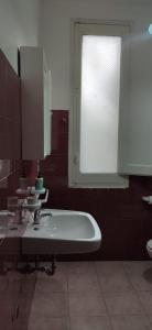 La salle de bains est pourvue d'un lavabo blanc et d'une fenêtre. dans l'établissement Villa Muia-Appartamento con giardino, à Parabita