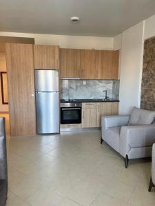 eine Küche mit einem Kühlschrank aus Edelstahl und einem Sofa in der Unterkunft Home 4U apt1, just 7km from airport in Markopoulo