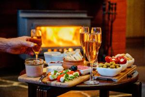 a table with two glasses of champagne and food and a fireplace at Southern Ocean Retreats - Deep Creek National Park in Delamere