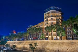 a tall building with palm trees in front of a wall at Gate Twenty Two Boutique Hotel in Nicosia