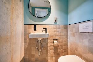 a bathroom with a sink and a toilet and a mirror at Villa Viva - ein Haus das Brunnen baut in Hamburg