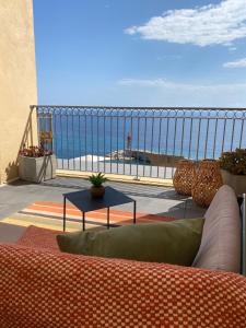 a couch on a balcony with a view of the ocean at Hôtel Des Gouverneurs in Bastia