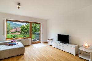 a living room with a television and a large window at Haus Gartenblick in Annweiler am Trifels