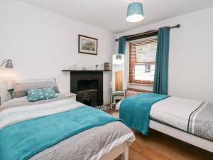 a bedroom with two beds and a fireplace at Jessie's Cottage in Kendal