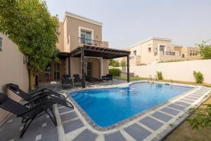 una piscina con sillas y una casa en OFFER-Book 4BR Villa and Ride at Luxury Yacht FREE en Dubái