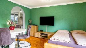 um quarto com uma cama e uma televisão numa parede verde em Ferienwohnung Arenda em Munzingen