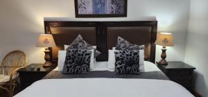 1 dormitorio con 1 cama con almohadas blancas y negras en Lagoon Lodge, en Knysna