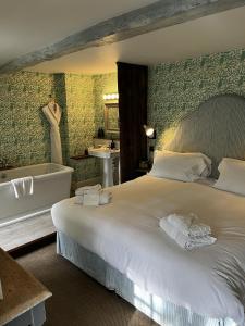 ein Schlafzimmer mit einem großen Bett und einer Badewanne in der Unterkunft The Swan Inn in Shipton under Wychwood