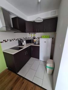 a kitchen with brown cabinets and a white refrigerator at SmartHomeApartman in Hajdúszoboszló