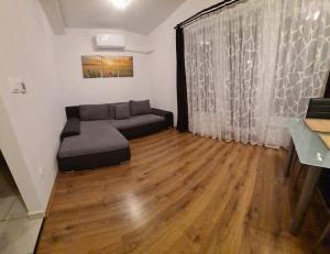 a living room with a couch and a wooden floor at SmartHomeApartman in Hajdúszoboszló