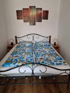 a bed with a floral comforter on top of it at SmartHomeApartman in Hajdúszoboszló