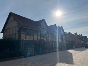 a building on a street with the sun behind it at The Old Coach House in Stratford-upon-Avon