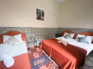una camera con due letti con lenzuola rosse e bianche di Sun Hostel a Marrakech