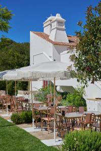 a group of tables and chairs in front of a building at Vermelho Melides - Relais & Châteaux in Melides