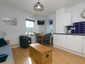 a kitchen and living room with white cabinets and a table at 5 St Brigids in St Ives