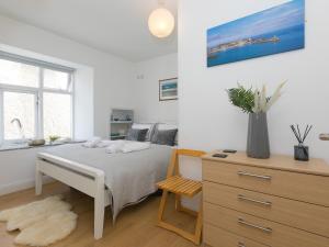 a white bedroom with a bed and a dresser at 5 St Brigids in St Ives