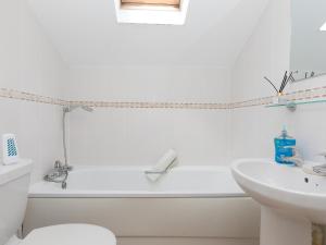 a white bathroom with a tub and a sink at 5 St Brigids in St Ives