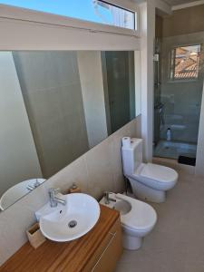 a bathroom with a sink and a toilet and a mirror at TuKaza - Guesthouse in Esposende