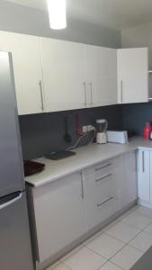 a kitchen with white cabinets and white appliances at Villa proche du Stade de France JO 2024 in La Courneuve