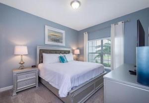 a blue bedroom with a bed and a window at Stunning Townhouses 5 Minutes away Disney! in Kissimmee