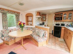 a kitchen with a couch and a table with a vase of flowers at Chill Out Holiday in Pencader