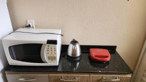 a microwave sitting on top of a black counter at Casa Confortável Mobiliada in Marília