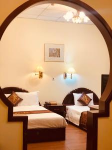 2 camas en una habitación de hotel con un arco en Ngọc Lan Hotel, en Ho Chi Minh
