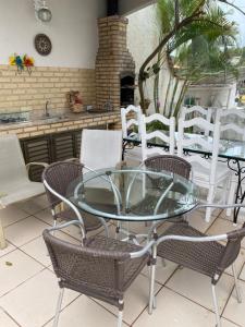 a glass table and chairs on a patio at CASA DE REVISTA em Cabo Frio in Cabo Frio