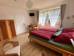 Schlafzimmer mit einem Bett mit roter Bettwäsche und einem Fenster in der Unterkunft Kleine-Radoase Ferienwohnung mit Super- Aussicht in Weilburg