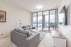 a living room with a couch and a tv at Cozy 2BD Apt w Waterview near Olympic Park in Sydney