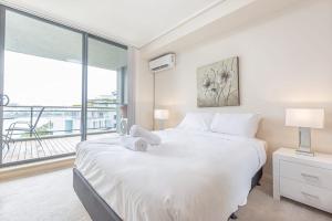 a bedroom with a large white bed and a large window at Cozy 2BD Apt w Waterview near Olympic Park in Sydney