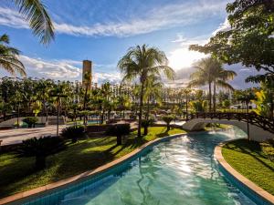 uma piscina num parque com uma ponte e palmeiras em Blue Tree Thermas de Lins Resort em Lins