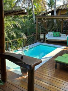 Villa Nicolle - Bahia - Praia do Espelho في برايا دو إسبيلهو: حمام سباحة مع أرجوحة على سطح خشبي