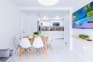 cocina blanca y comedor con mesa de madera y sillas blancas en Serenity Lodge Condo, en Miami