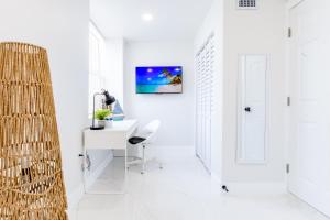 Serenity Lodge Condo في ميامي: غرفة بيضاء مع مكتب وتلفزيون على الحائط