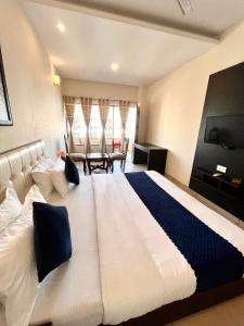 1 dormitorio con 1 cama blanca grande y TV en JB Residency Zirakpur !! Top Rated & Most Awarded Property in Zirakpur, en Zirakpur