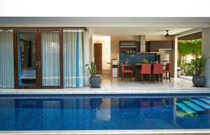 a house with a swimming pool next to a kitchen at Indi Villas - The Bhadra Villa in Seminyak