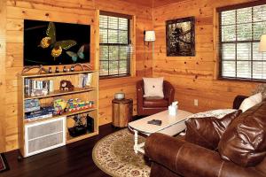 sala de estar con sofá y TV en Mountain Laurel Cabin, en Cosby