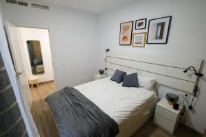 um quarto com uma cama com lençóis brancos e almofadas azuis em 0B PlusUltra piso de 1 dorm em Alicante
