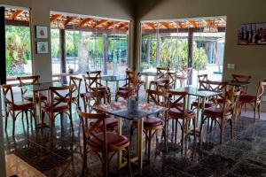 a dining room with tables and chairs and windows at Spa Agua Milagrosa in Cuiabá
