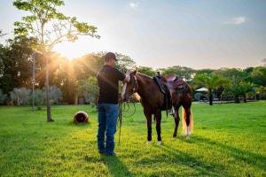 a man standing next to a horse in a field at Spa Agua Milagrosa in Cuiabá