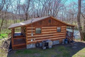 a large wooden cabin in the woods next to a river at Creekside Memories Cabin in Cosby