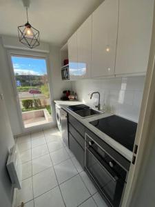 a white kitchen with a sink and a window at Mulhouse grand T2 -  La Fonderie -Parking gratuit in Mulhouse +4 photos